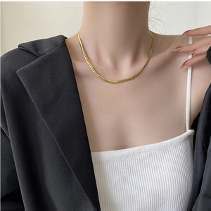 Close-up of a minimalist golden snake bone chain necklace on a model's neck