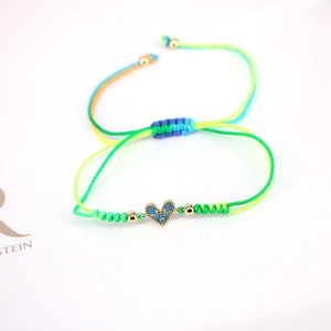 Detail of adjustable woven lucky bracelet featuring a heart pendant with blue zircon stones
