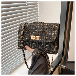 Close-up of black tweed fabric texture and golden rotary lock on the crossbody bag