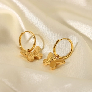 Macro shot of 18K gold-plated butterfly earrings on smooth white silk fabric