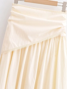Detail of cream pleated maxi skirt featuring delicate lace trim and textured fabric