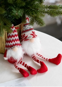 Close-up of knit Christmas gnomes with striped long legs and snowflake pattern hats