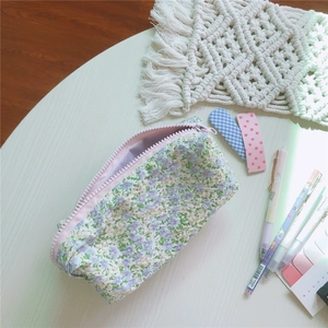 Detalle del estuche de lona floral con cremallera rosa en un escritorio estético
