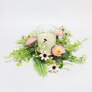 Close-up of a white scented candle jar surrounded by a romantic pink and white flower wreath