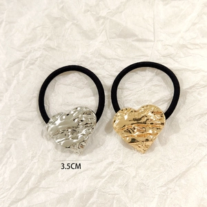 Detail of gold and silver heart metal hair ties with 3.5cm textured charms on black elastic