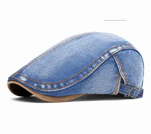 Detail of dark blue denim flat cap with brown leather brim and contrast stitching