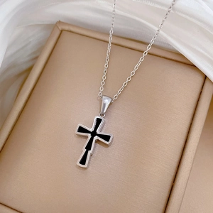 Macro shot of silver titanium steel cross pendant with black inlay on silk jewelry box