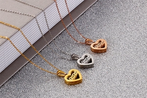 Detailed view of heart-shaped MAMA pendants in gold, silver, and rose gold finishes