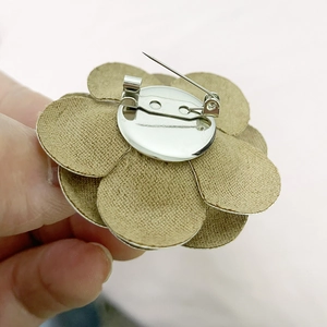Detail view of the back silver pin and secure clasp on the beige floral camellia brooch