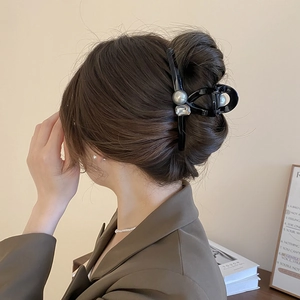 Vintage acrylic hair claw with pearls and rhinestones shown on a woman from the side