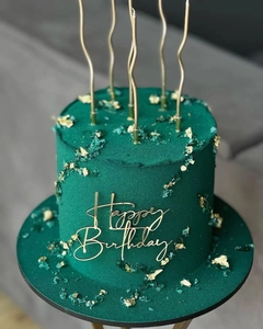 Detailed view of dark green frosted cake with gold Happy Birthday topper and candles
