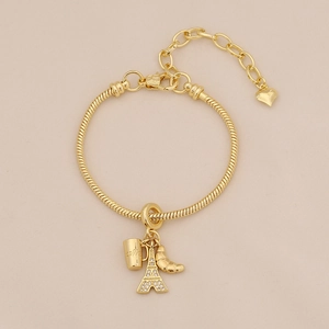 Detailed view of gold snake chain bracelet with Eiffel Tower and coffee cup charms