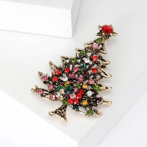 Vintage gold Christmas tree brooch with colorful rhinestones on white geometric pedestal