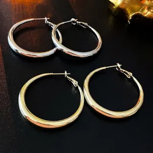 Minimalist geometric hoop earrings in polished gold and silver finishes on leather