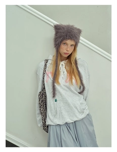 Detail of gray cat ear knit hat with long tassels paired with casual winter outfit