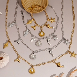 Golden and silver ocean necklaces with shell and starfish charms on a beach-themed background