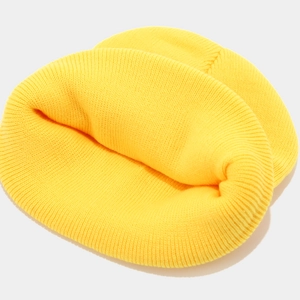 Detailed knit texture of a warm ginger yellow beanie hat with vertical ribbed patterns