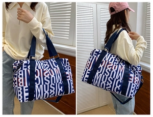 Close-up of a blue canvas travel bag with BE MUSIC letter pattern and adjustable shoulder strap