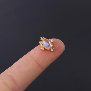 Macro shot of 20G stainless steel moonstone stud earring with rainbow glow on a fingertip