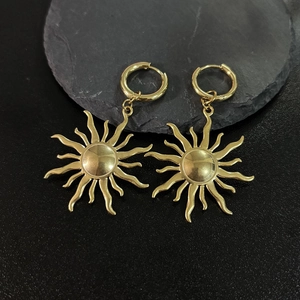 Detailed close-up of 18K gold plated sun heart earrings on dark textured background