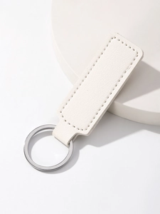 Detail showing white lychee pattern leather texture and polished metal ring on business keychain