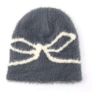 Close-up of grey fluffy knit beanie with white jacquard bow pattern and fuzzy texture