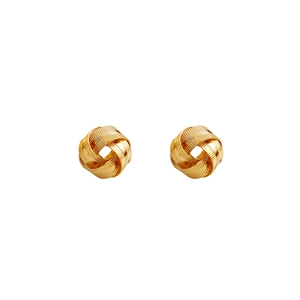 Detail shot of golden knot earrings featuring intricate spiral engraved texture and metal finish