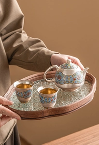 Close-up of enamel tea set with blue floral pattern on wood and glass tray