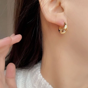 Macro shot of gold hoop earrings with starburst zircon inlay and vintage crescent design