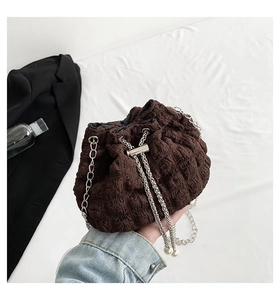 Detail of dark brown pleated drawstring bucket bag with silver chain and pearl accent