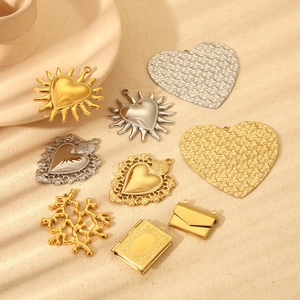 Flat lay of vintage gold and silver heart charms, envelope pendants, and locket accessories