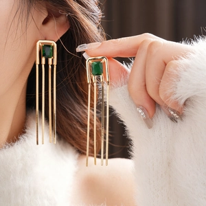 Detail of square green zircon tassel earrings on model with vintage gold finish