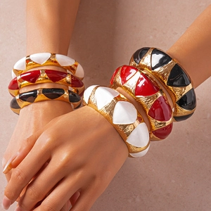 Macro detail of enamel gold cuff bracelets with textured finish and vibrant drip oil colors