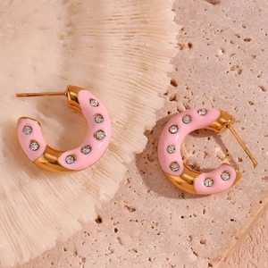 Macro shot of pink enamel hoop earrings with white crystals on a white coral base