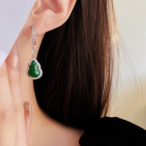 Detail of vintage teardrop earrings with green jade stones and zircon on a female model