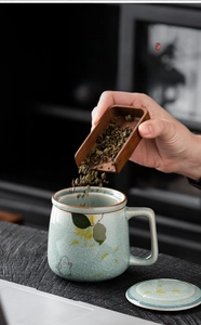 Detail of green ice-crack glaze ceramic mug with rabbit pattern and wooden tea scoop