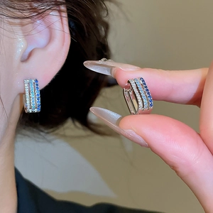 Macro detail of triple-row silver ear cuffs with blue and white sparkling zircon stones