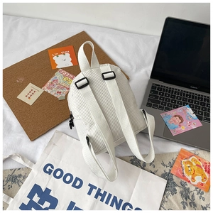 Detail view of white corduroy mini backpack back panel and adjustable shoulder straps