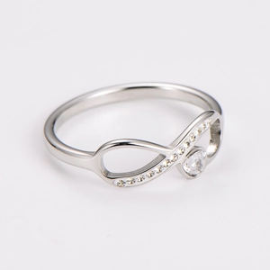 Macro shot of silver infinity ring with heart-shaped zircon and pavé diamond setting