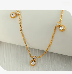 Macro detail of gold plated necklace featuring three round bezel-set zircon pendants