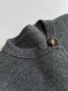 Detail of grey knitted cardigan showing ribbed texture and a marble pattern button