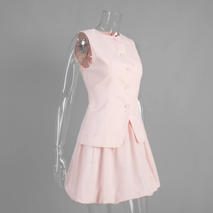 Détail du gilet sans manches rose boutonné et de la jupe plissée à taille haute assortie