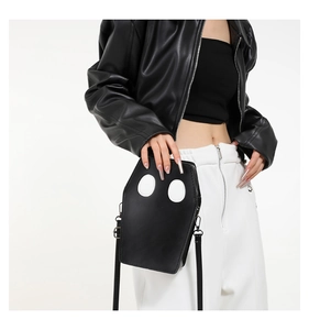 Detail of coffin shaped black crossbody bag with ghost eye appliques worn by a model