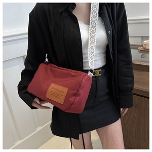 Detail of red nylon crossbody bag featuring stylish patterned wide shoulder strap