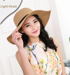 Detail of light khaki straw hat featuring wide wavy brim and elegant black ribbon decor