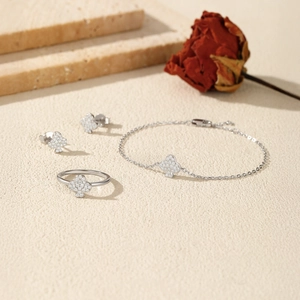 Elegant silver clover jewelry set with sparkling studs, ring and bracelet on stone