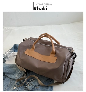 Detail view of khaki sports travel bag with brown leather handles on bedsheet