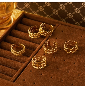 Detail of five 18K gold plated hollow floral rings displayed in a brown velvet jewelry box