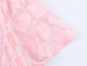 Gros plan détaillé de la broderie florale rose sur la texture du tissu organza