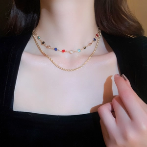 Detail of layered gold necklace with colorful zircon stones and twisted metal chain